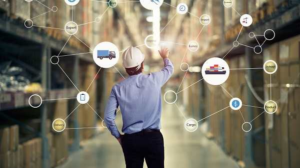 A person is touching on the supply chain dots that have texts such as export, import, business, customer, delivery, product along with icons of lorry, dollar and ship, seen with a backdrop of a warehouse.