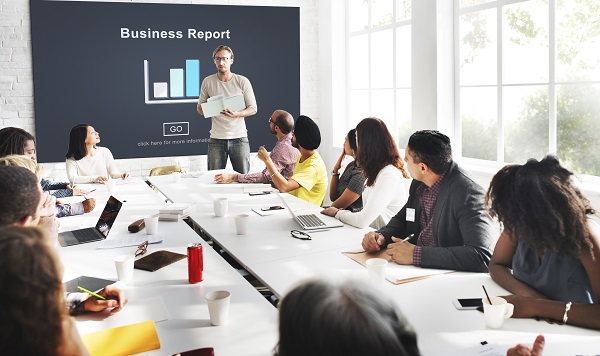 Employees sitting in a conference room with the business reports displayed on the black board.
